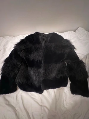 Svart pälsjacka med struktur - Säljer en svart pälsjacka från vero moda.  Perfekt för dig som vill ha en statement piece till vintergarderoben. Fodrad insida och klassisk rund hals. 