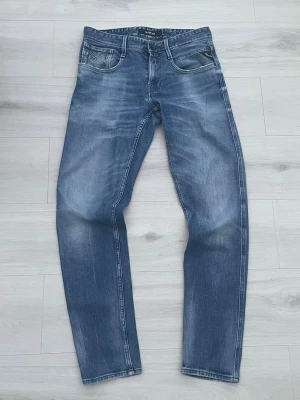 Blå jeans från Replay - Snygga blå jeans från Replay Anbass. Jeansen har snygga fades och tydliga sömmar, samt en svart patch bak i midjan. Perfekta för en avslappnad och trendig look.