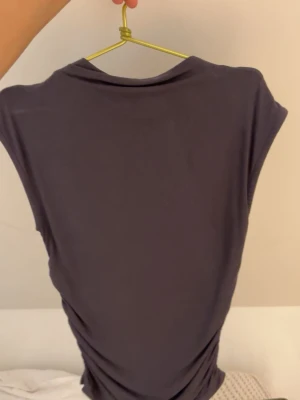 Mörkgrå croppad topp - En enkel och stilren mörkgrå croppad topp med korta ärmar. Perfekt för att matcha med jeans eller kjol. Toppens material känns mjukt och stretchigt, vilket gör den bekväm att bära hela dagen.