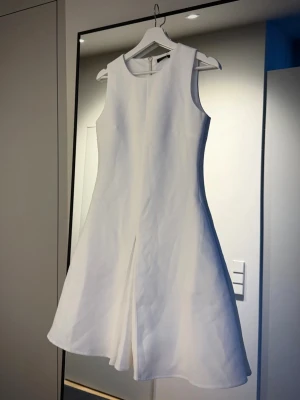 Vit sommarklänning - Vit kortklänning i A-linjeformad modell med rund halsringning och ärmlös design. Klänningen har en synlig dragkedja i ryggen och det bästa - FICKOR☺️ 