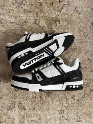 Louis Vuitton svartvita sneakers - Säljer ett par Louis Vuitton sneakers i svart och vitt med klassiskt monogrammönster. Skorna har lågt skaft, vita skosnören och detaljer i både läder och textil. Snygg kontrast mellan svart och vitt samt tydlig LV-logga på sidan och sulan.