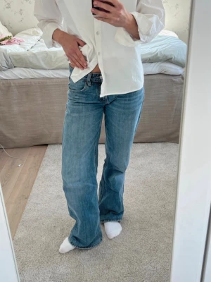 Lågmidjade vida Zara jeans - Lågmidjade vida Zara jeans i storlek 32!     Midjemått: 35cm                                              Innerbenslängd: 73cm.                                  Jeansen är uppsydda (syns på bilden)