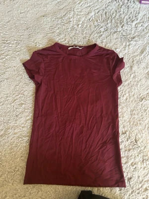 Vinröd t-shirt från 157 - En basic vinröd t-shirt från 157 i storlek M. T-shirten har rund halsringning och korta ärmar. Perfekt att matcha med jeans eller shorts för en enkel och snygg look.