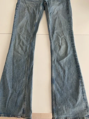 Ljusblå utsvängda jeans - Säljer ett par ljusblå jeans med utsvängda ben och klassisk femficksmodell. Från Gina