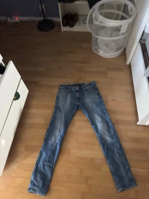 Blåa replay anbass jeans W32 L34  - Säljer ett par blå jeans med rak passform och klassisk femficksdesign. Jeansen har en snygg tvättad look och är tillverkade i slitstarkt denimtyg. Perfekta för dig som gillar en enkel och tidlös stil. Kolla bilder på defekter på midjan bak.