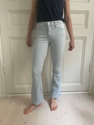 Ljusblå bootcut jeans med hög midja - Snygga ljusblå jeans med bootcut-modell och hög midja. Jeansen har klassiska fem fickor och stängs med dragkedja och knapp. Perfekta för dig som gillar en avslappnad men trendig stil.