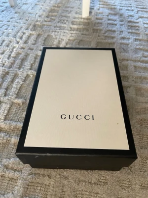 Gucci vita sneakers med kardborreband - Snygga vita sneakers från Gucci med klassiska gröna och röda ränder på sidan. Skorna har två breda kardborreband och detaljer i grönt och rött på hälen. Tillverkade i läder och levereras i originalkartong.