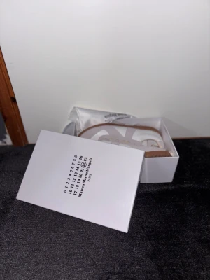 Maison Margiela sneakers vita/beige - Maison Margiela sneakers i vitt och beige med ovandel i läder och mocka, klassisk gummisula och diskret logga på plösen. Snygg minimalistisk design som passar till många olika stilar.