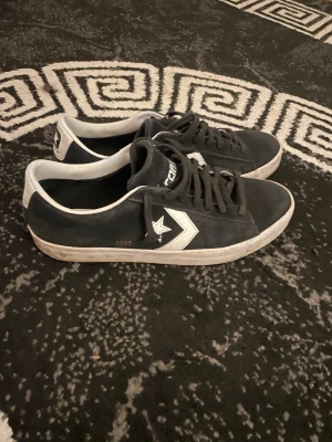 Svarta Converse CONS sneakers - Svarta Converse CONS sneakers i mocka med vita detaljer och klassisk stjärnlogga på sidan. Lågt skaft och vit sula ger en clean och tidlös look. Perfekta för dig som gillar streetstyle och vill ha ett par sköna och snygga skor till vardags.