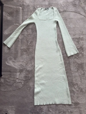 Ljusgrön ribbad långklänning Gina Tricot - Långklänning från Gina Tricot i ljusgrön nyans. Klänningen är ribbad, har lång ärm och fyrkantig ringning. Materialet är stickat och stretchigt vilket ger en bekväm passform. Perfekt för dig som gillar stilrena och enkla plagg.