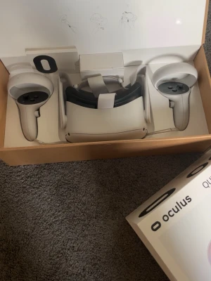 Oculus Quest 2 VR-headset med kontroller - Säljer ett Oculus Quest 2 VR-headset i vit plast med tillhörande två handkontroller. Headsetet har justerbart band och modern, stilren design. Perfekt för att uppleva VR-spel och appar trådlöst. Allt ligger i originalförpackning. Den funkar fortfarande jätte bra har haft den ett litet tag nu och funkar mycket bra. Dom är väldigt roliga att spela med särklilt om man gillar virtual reality.