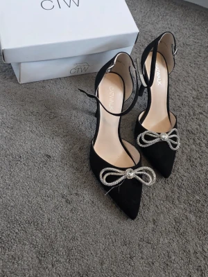 Svarta pumps med strassrosett Catwalk - Snygga svarta pumps från Catwalk storlek38. Dom är i bra skick använd en gång bara men passar inte mig längre. Pris kan diskutera 