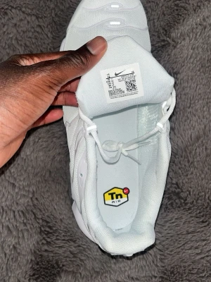 Nike Air Max Plus vita sneakers - Nike Air Max Plus sneakers i helvitt med Tn Air-detalj på innersulan. Skorna har en sportig siluett, synlig Air-enhet i sulan och är tillverkade i mesh och syntetmaterial. Perfekta för dig som gillar streetwear och vill sticka ut med en clean look.