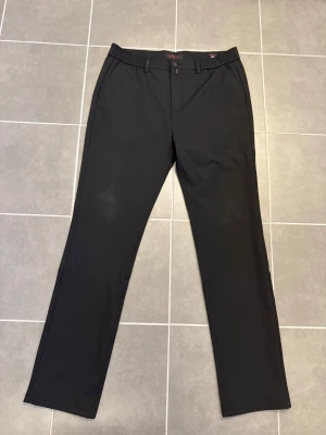 Svarta chinos från Kiton - Snygga svarta chinos från Kiton med rak passform och elastisk midja. Byxorna har klassiska sidofickor och bälteshällor. Materialet är mjukt och bekvämt, perfekt för dig som vill ha stilrena och enkla byxor.