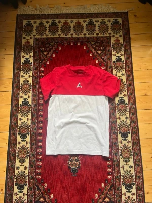 Jordan rödvit t-shirt med logga - Säljer en snygg t-shirt från Jordan i rött och vitt. T-shirten har korta ärmar, klassisk passform och en tydlig Jordan-logga broderad på bröstet. 