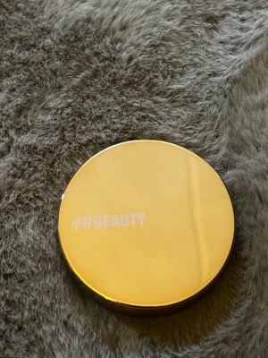 Bronzer från H&M Beauty i guldig dosa - Bronzer från H&M Beauty i en rund, guldig metallförpackning. Produkten har en varm brun nyans med lätt shimmer och är pressad i kompakt form. Perfekt för att ge ansiktet en solkysst look och definiera ansiktsdragen. Testad en gång, tyvärr inte min färg