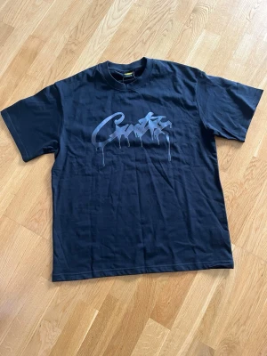 Svart Corteiz T-shirt  - Svart Corteiz T-shirt med logga på bröstet. Etiketten är fortfarande på. Funkar även om man har storlek L.
