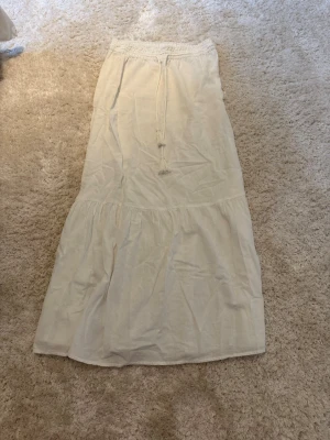 Vit långkjol med snörning - Lång, luftig vit kjol från vero Moda i stroken S. Kjolen är 100 cm från midjan och ner. Använd ett fåtal gånger. 