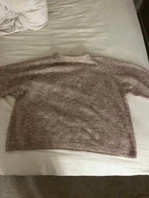 Beige stickad tröja från 157 - Mysig stickad tröja i beige nyans från 157, med rund hals och ribbstickade detaljer vid hals, ärmslut och nederkant. Perfekt för lager-på-lager och enkel att matcha med jeans eller kjol. Materialet är mjukt och ger en avslappnad look.