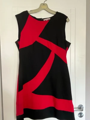 Svart och röd ärmlös klänning Anna Field - Snygg ärmlös klänning med grafiskt mönster i svart och rött. Klänningen har rund halsringning och rak passform, perfekt för dig som gillar en modern och färgstark stil. Tillverkad i ett mjukt och bekvämt polyestertyg.
