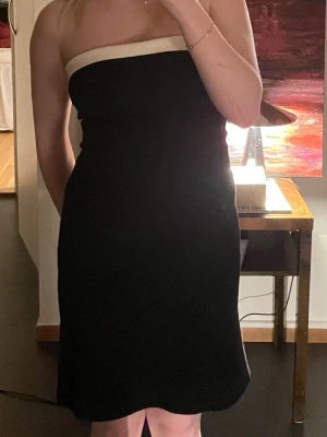 Svart bandeu klänning med vit kant - Axelbandslös svart klänning från bikbok med vit kant upptill. Klänningen har en enkel och stilren design, perfekt att dressa upp samt dressa ner 🥰