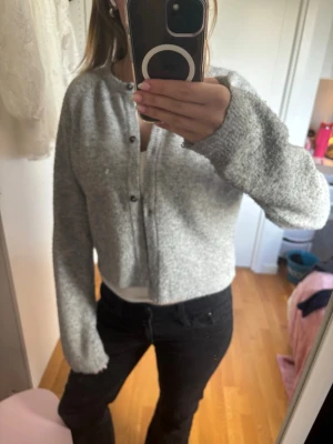 Grå kofta från Lindex🫶🏻 - Mysig grå kofta från Bik Bok med rund halsringning och knappar framtill. Koftan är stickad och har långa ärmar samt en lite boxig passform. Perfekt att slänga på sig när det är kyligt ute. Super gullig!🤍