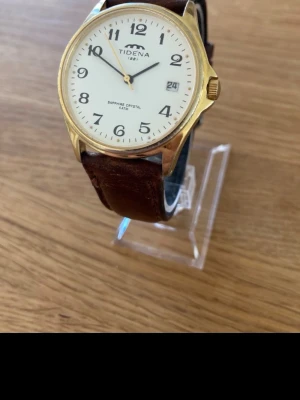 Tidéna Sapphire Gold Dress 38mm Herrur - Säljer en snygg stilren herrklocka från anrika svenska Tidena i nyskick enligt bilder. Fungerar utmärkt med nytt batteri, originalarmband i äkta läder, datumvisare, vattentät, safirglas som inte repar osv.  Nypris: 2000 SEK Begagnat värde: 1100 SEK Mitt pris: 689 SEK  Skickas alltid snabbt och spårbart. Skriv vid frågor och se gärna mina andra annonser!   GRATIS: För återkommande kunder erbjuder jag personlig experthjälp för dig att göra nya fynd (nytt & begagnat). Fråga för mer info!  Varumärke