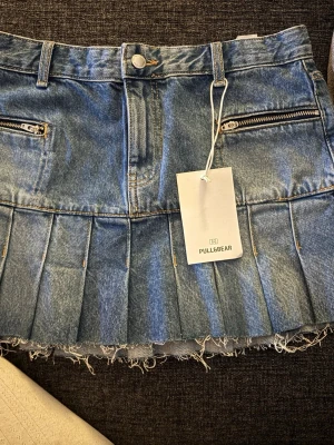 Mini jeans kjol  - Säljer en kort blå jeanskjol från Pull&Bear, helt ny med prislappen kvar. 