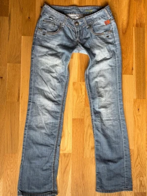 Ljusblå lågmidjade jeans - Snygga ljusblå jeans från patrol med klassisk femficksdesign och subtila slitningar. Jeansen har  raka och detaljerade sömmar samt logopatch på bakfickan. Perfekt för dig som gillar en avslappnad och trendig look. Jeansen har lagats av tidigare ägare, jag har använt flertal gånger och inte märkt av de💞
