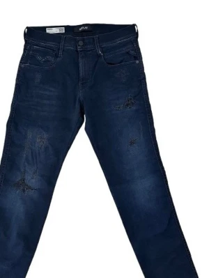 Mörkblå jeans med slitningar - Säljer ett par mörkblå jeans med coola slitningar på framsidan. Jeansen har raka ben och klassisk femficksdesign. Materialet är denim och färgen är djup blå. Perfekt för dig som gillar en avslappnad och trendig look.