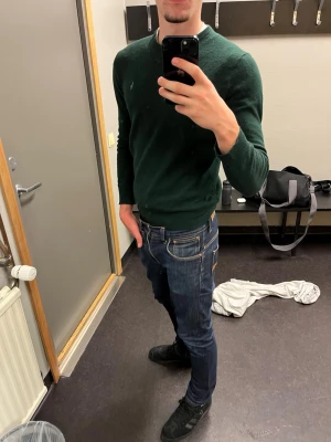 Mörkgrön Polo Ralph lauren  tröja - Säljer en stilren mörkgrön tröja från Polo Ralph lauren med rund halsringning och långa ärmar. Tröjan är enkel och passar perfekt till jeans. Materialet är mjukt och bekvämt i 100% bomull, idealiskt för att hålla värmen under kyliga dagar. Ett litet hål på högersida rygg men svårt att märka av, skriv om ni undrar nått