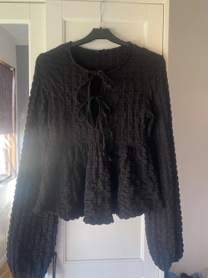 Svart peplumblus - En svart peplumblus från Gina Tricot med knytdetaljer framtill Blusen är använd men fortfarande bra skick Storlek XS !!Har katter hemma!! Förhandlar gärna om priser 