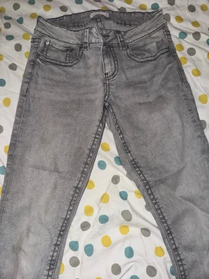 Grå jeans från Perfect Jeans gina tricot - Säljer ett par grå jeans från Perfect Jeans med klassisk femficksdesign och snygga detaljer på bakfickorna. Jeansen har en slim fit passform och är tillverkade i ett mjukt denim-material. Perfekta för dig som gillar en stilren look.