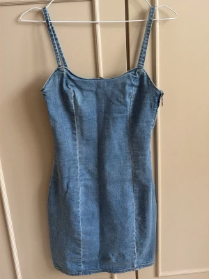 Tight jeansklänning - Säljer en snygg blå jeansklänning med smala axelband och figurnära passform. Mycket stretch i. Från divided stl 36.