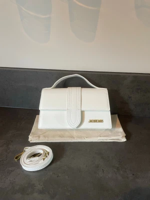 Vit Jacquemus väska - Hej säljer denna vita jaquemosväska och band och dustbag ingår. Den är i nyskick men har tyvärr inget kvitto. Priset är diskuterbart och hör av dig vid minsta lilla//a_garderoben✨