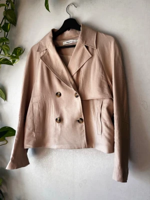 Snygg beige kavaj i skepparmodell - Snygg dubbelknäppt oversized kavaj från Kappahl "limited edition". Riktiga fickor!  Snygg oljerocksdetalj i ryggen.  Storlek medium men jag har använt den när jag haft strl 44-46. 51-52cm mellan armhålorna när den är knäppt. Generösa ärmar.  Noppig på flera ställen, inget en noppborttagare inte klarar av. Se bilder.  Se även andra annonser för bundle! 🌷  Avhämtning i Gävle/Uppsala går att lösa (skriv pm innan köp) 