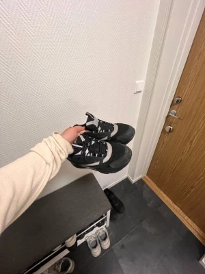 CD  - Säljer ett par svarta chunky sneakers med vita detaljer och grov sula. Skorna har mesh och syntetmaterial på ovandelen samt svarta skosnören. Perfekta för dig som gillar en sportig och trendig look.