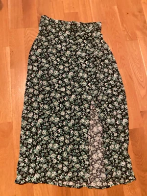 Grön blommig långkjol - Säljer en grön blommig långkjol. Kjolen är köpt från lindex och har slits vid väntra benet framtill! Skriv gärna om ni har frågor.
