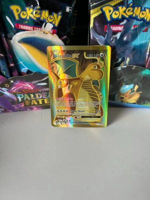 Dragonite EX Pokémonkort holo - Säljer ett Dragonite EX Pokémonkort med holografisk yta. Kortet har färgstarka detaljer i guld, grönt och regnbågsskimrande toner. Perfekt för samlare eller Pokémonfans som vill utöka sin kortsamling.