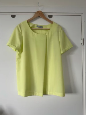 Samsøe Samsøe - gul kortärmad blus - storlek S - Härlig gul kortärmad topp från Samsøe Samsøe i storlek S. Stilren modell med rund halsringning och en unik omlottdetalj framtill som ger en modern touch. Ärmarna är korta och har en uppvikt kant. Passar bra för en avslappnad men stilfull look. Nypris 1600:-. Mycket gott skick, som ny!