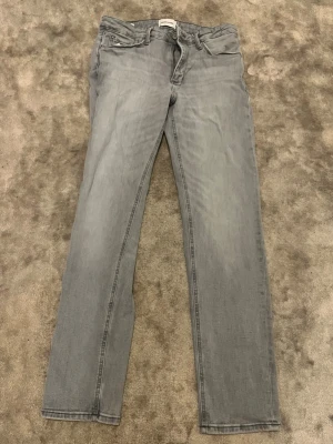 Ljusgrå raka jeans - Snygga ljusgrå jeans med rak passform och klassisk femficksdesign. Jeansen har bälteshällor och dragkedjegylf. Perfekta för en avslappnad och trendig look. Materialet är denim i bomull.