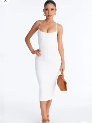 Vit tight långklänning med smala axelband från FashionNova helt oanvänd med prislapp. - Säljer en stilren vit långklänning med smala axelband och figurnära passform. Klänningen har en enkel och elegant design med rundad urringning och ärmlös siluett. Perfekt för dig som gillar minimalistisk stil. Helt oanvänd klänning från FashionNova med prislapp.
