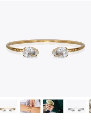 Tunn guldfärgad ring med stenar - En stilren och tunn ring i guldfärgad metall med två klara stenar framtill. Ringen har en minimalistisk design och passar perfekt för dig som gillar diskreta smycken med en touch av elegans.