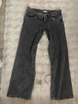 Grå baggy jeans med vintagekänsla - Ett par grå jeans med baggy passform och klassisk femficksdesign. Jeansen har en något tvättad look som ger en cool vintagekänsla. Perfekta för en avslappnad och trendig stil.