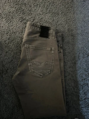 Beiga jeans från Replay - Säljer ett par snygga beiga jeans från Replay med klassisk femficksdesign och raka ben. Jeansen har en diskret logga på bakfickan och är tillverkade i mjukt bomullsmaterial med lite stretch för extra komfort. Perfekta för en avslappnad och stilren look. Warning lappar saknas. Skicka inte tillbaks. 
