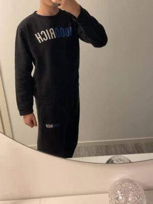Svart HOODRICH set - S - Säljer ett svart set från HOODRICH med tryckt logga i blått och vitt över bröstet. Plaggen på bilderna kommer med alltså sweatshirten och byxorna ingår.