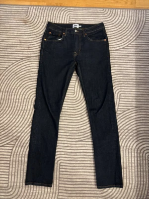 Mörkblå jeans från 157 - Säljer ett par mörkblå jeans från 157 med klassisk femficksmodell och kontrastsömmar. Jeansen har normal midja, raka ben och är tillverkade i ett stretchigt denimtyg för extra komfort. Perfekta för en clean och stilren look.