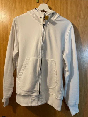 Äkta Vit parajumper zip hoodie - Säljer en vit parajumper zip up då själv inte har någon användning för den. Den är köpt på Urban Modern i Halmstad för 3100kr. Kvitto finns!