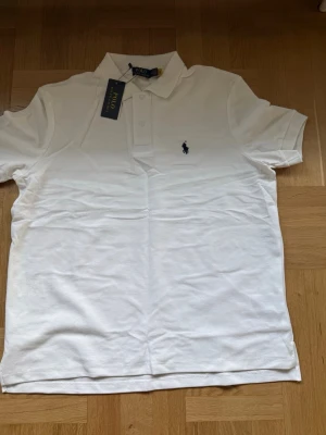 Ralph Lauren vit pikétröja – storlek M - Snygg och tidlös vit pikétröja från klassiska Ralph Lauren. Har en mycket fin passform och är tillverkad i ett mjukt och slitstarkt bomullsmaterial med loggan på bröstet. ✔ Storlek: M ✔ Märke: Ralph Lauren ✔ Färg: Vit ✔ Elegant och sportig look 📩 Skicka ett meddelande vid frågor eller prisförslag! 🛍 Lägg till i ett paket för att spara upp till 20% rabatt! 📦 Garanterad leverans samma eller nästa dag 🌟 
