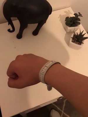Dior armband - Grått armband från Christian Dior i textil med broderad logga och snygga tofsar. Armbandet har justerbar knytning så det passar de flesta handleder. Perfekt accessoar för att ge din look en exklusiv touch.
